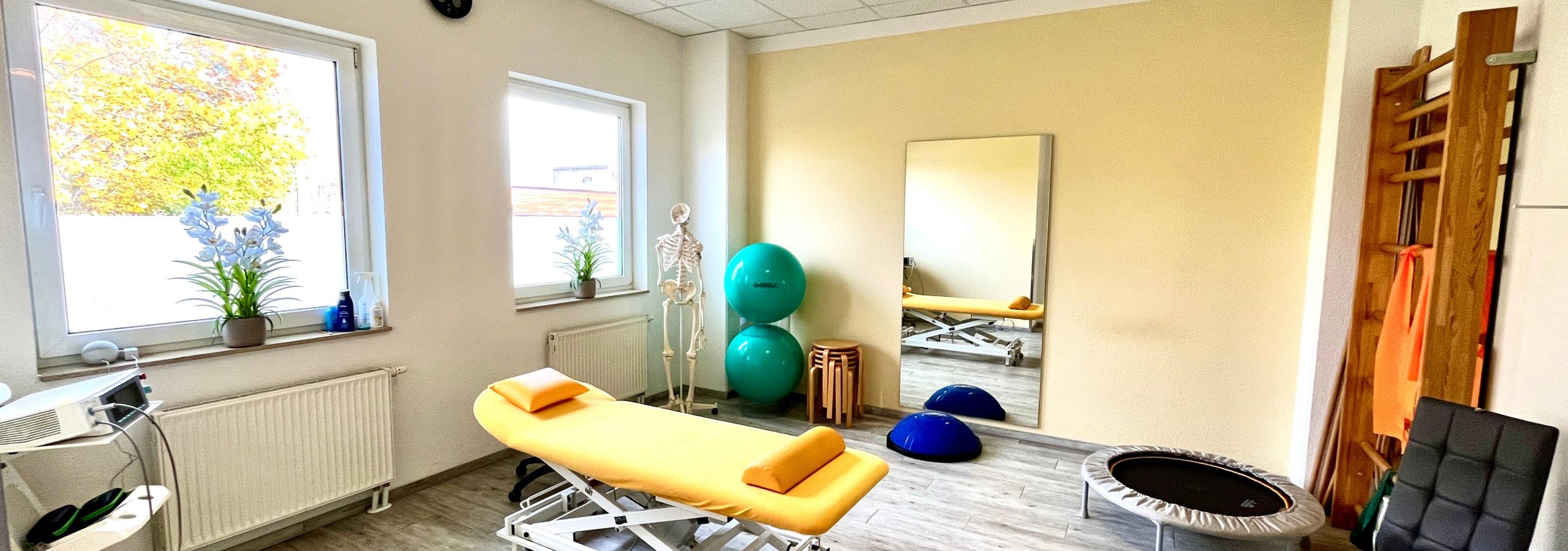 Helle und freundliche Physiotherapieräume mit Therapieutensilien.